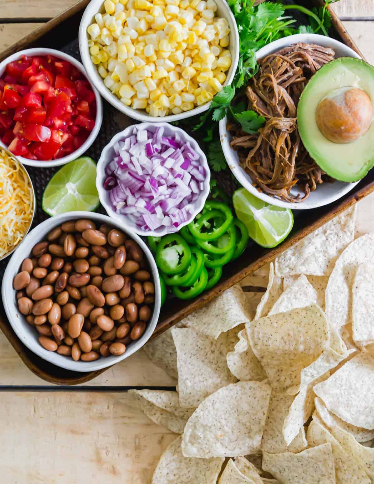 Repurpose leftover BBQ brisket with this easy nacho recipe. Pinto beans, corn, red onions, tomatoes and cheese make these simple but delicious nachos!