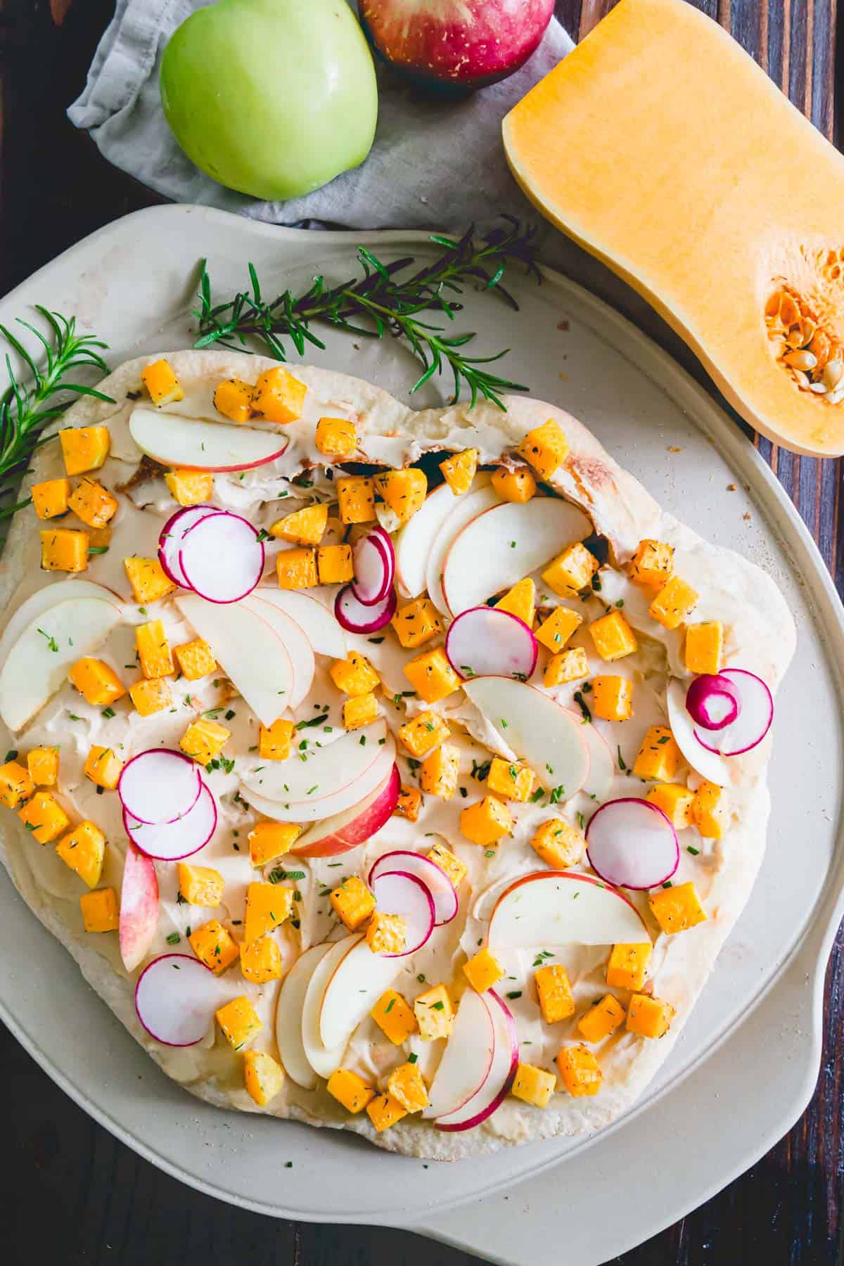rosemary seasoned roasted butternut squash cubes, thinly sliced radishes and crunchy apple slices top this hummus pizza for a delicious fall meal
