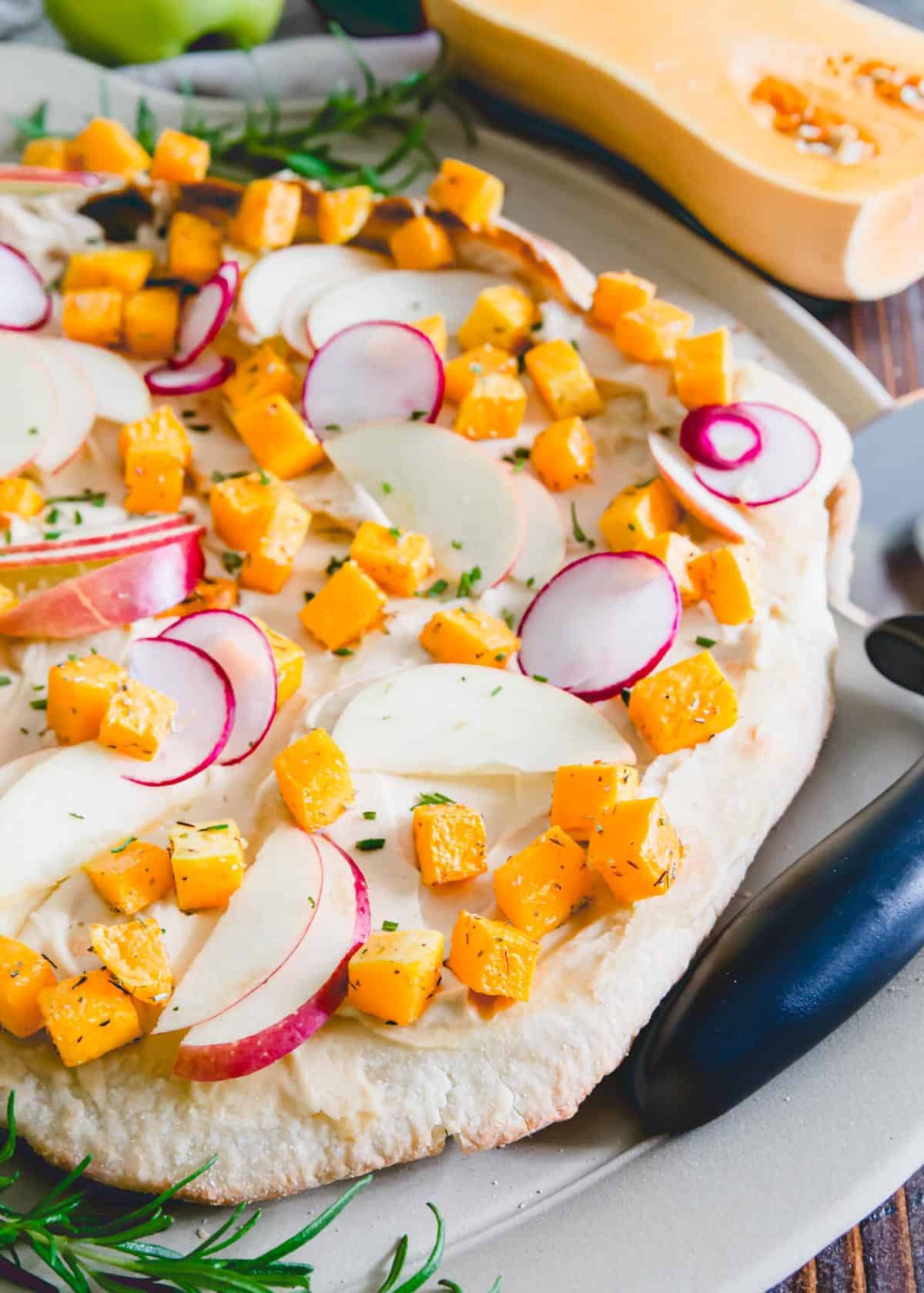 Try a healthier twist to traditional cheese pizza with this hummus pizza! Topped with roasted rosemary butternut squash, crunchy tart apples and thinly sliced radishes, it's a delicious vegetarian spin for fall.