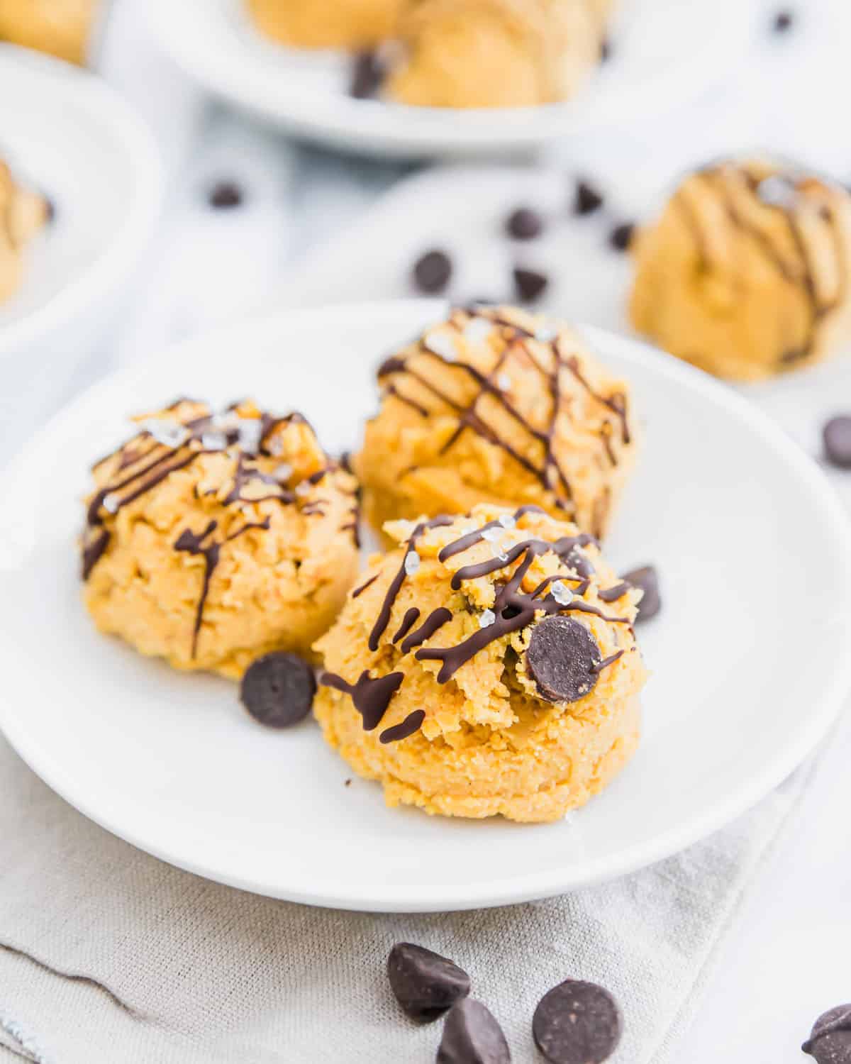 This edible, no-bake pumpkin cookie dough is shaped into bite-sized balls studded with chocolate chips and flaky sea salt for a healthy, vegan & gluten-free fall treat!