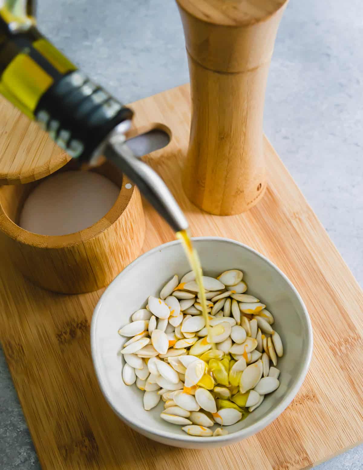 cleaned squash seeds being tossed with extra virgin olive oil