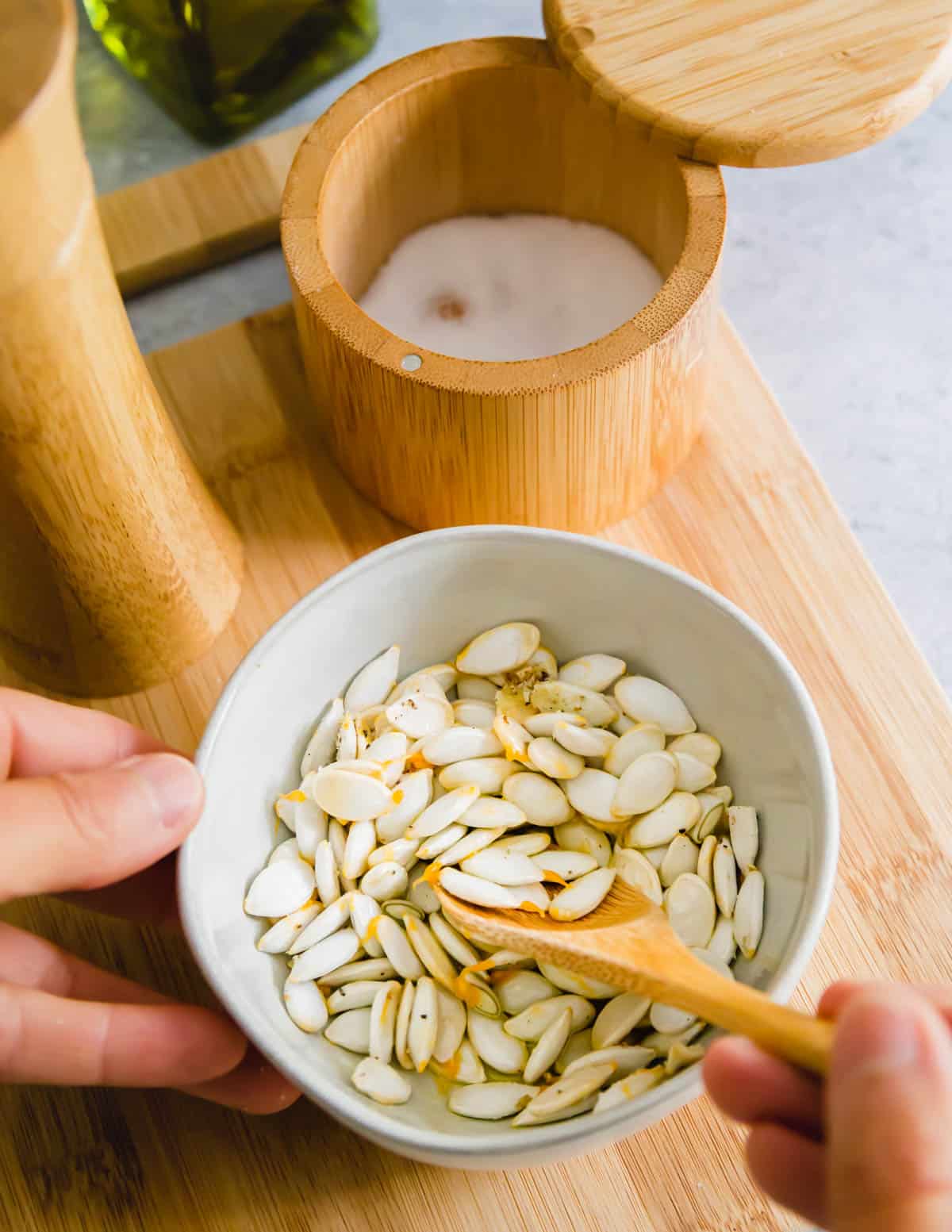 seasoning squash seeds with olive oil, kosher salt and black pepper before roasting