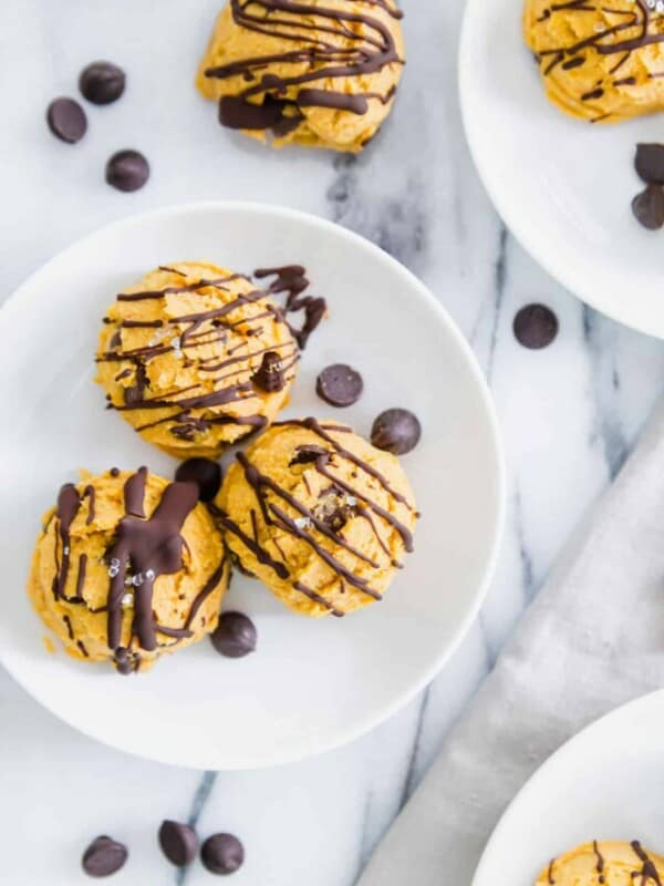 Pumpkin chocolate chip cookies on white plates with chocolate drizzle.