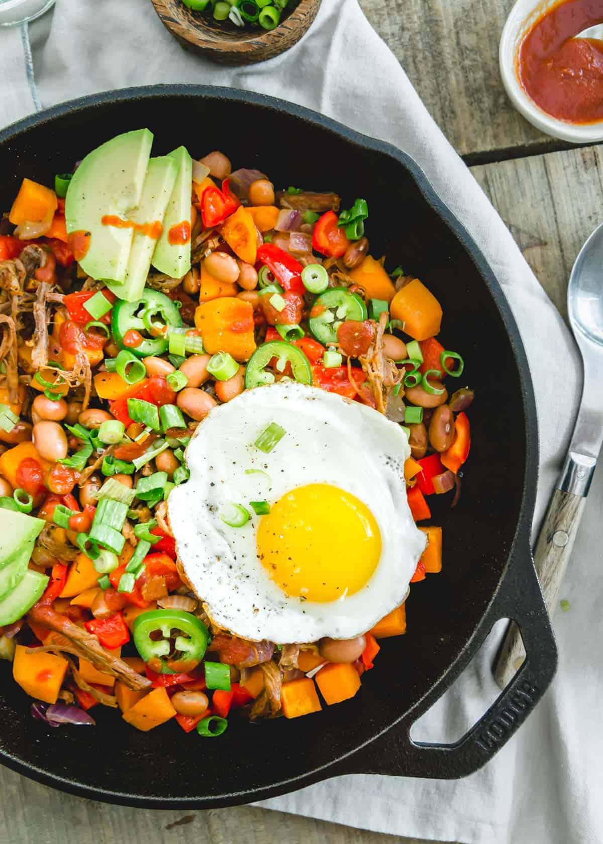 This easy skillet brisket hash recipe includes beans, sweet potatoes, peppers and a fried egg on top.