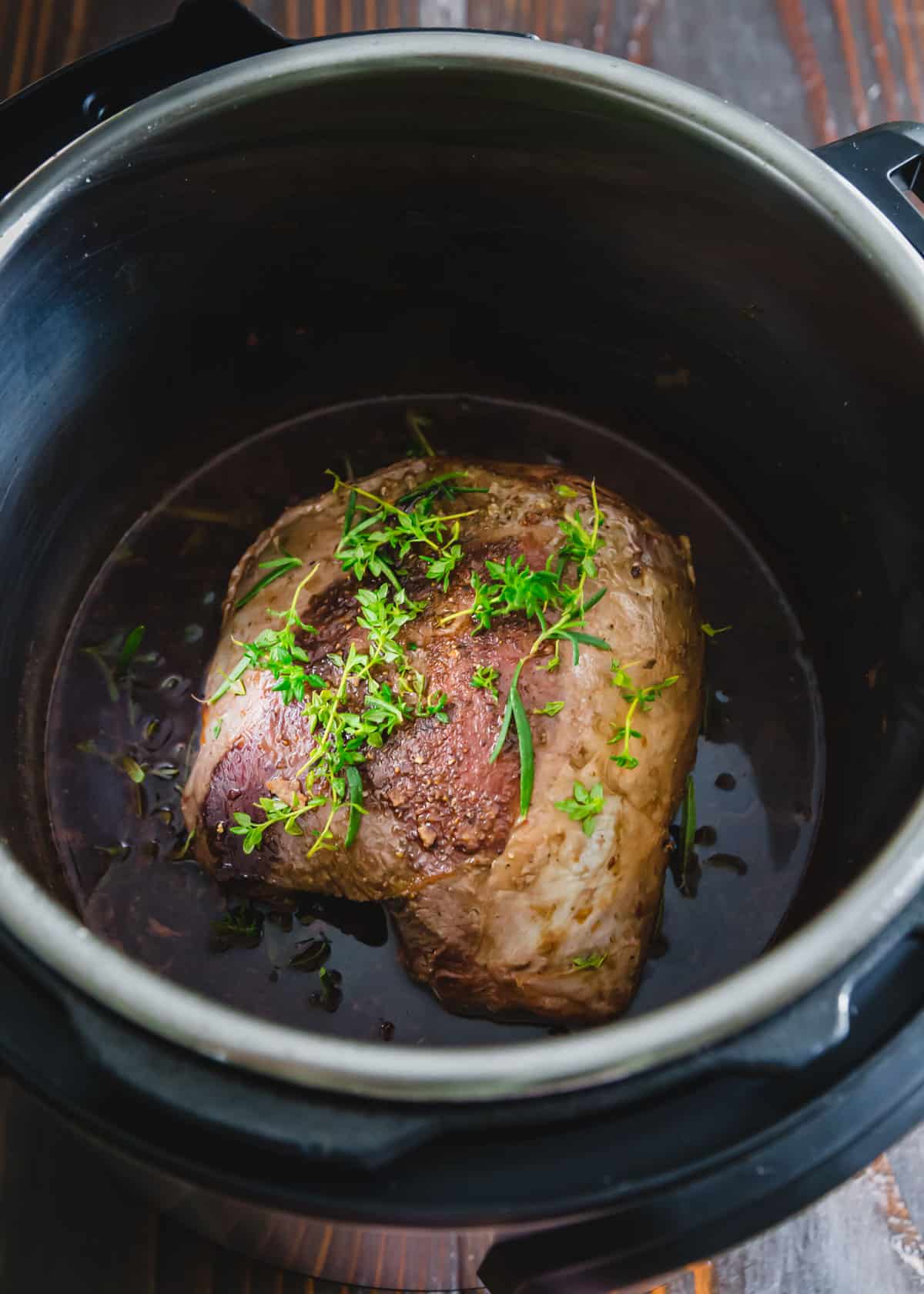 venison roast in the Instant Pot with fresh herbs before cooking
