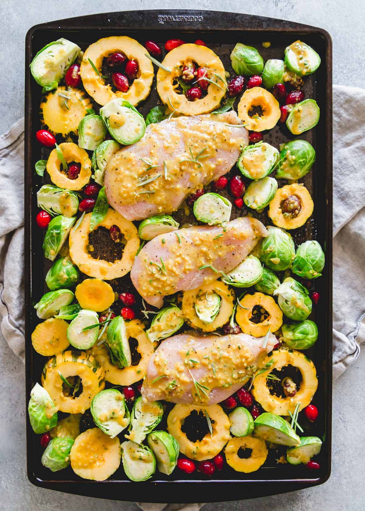 Easy fall dinner made on one pan with  chicken breasts, delicata squash, Brussels sprouts, cranberries and a maple mustard sauce with rosemary.