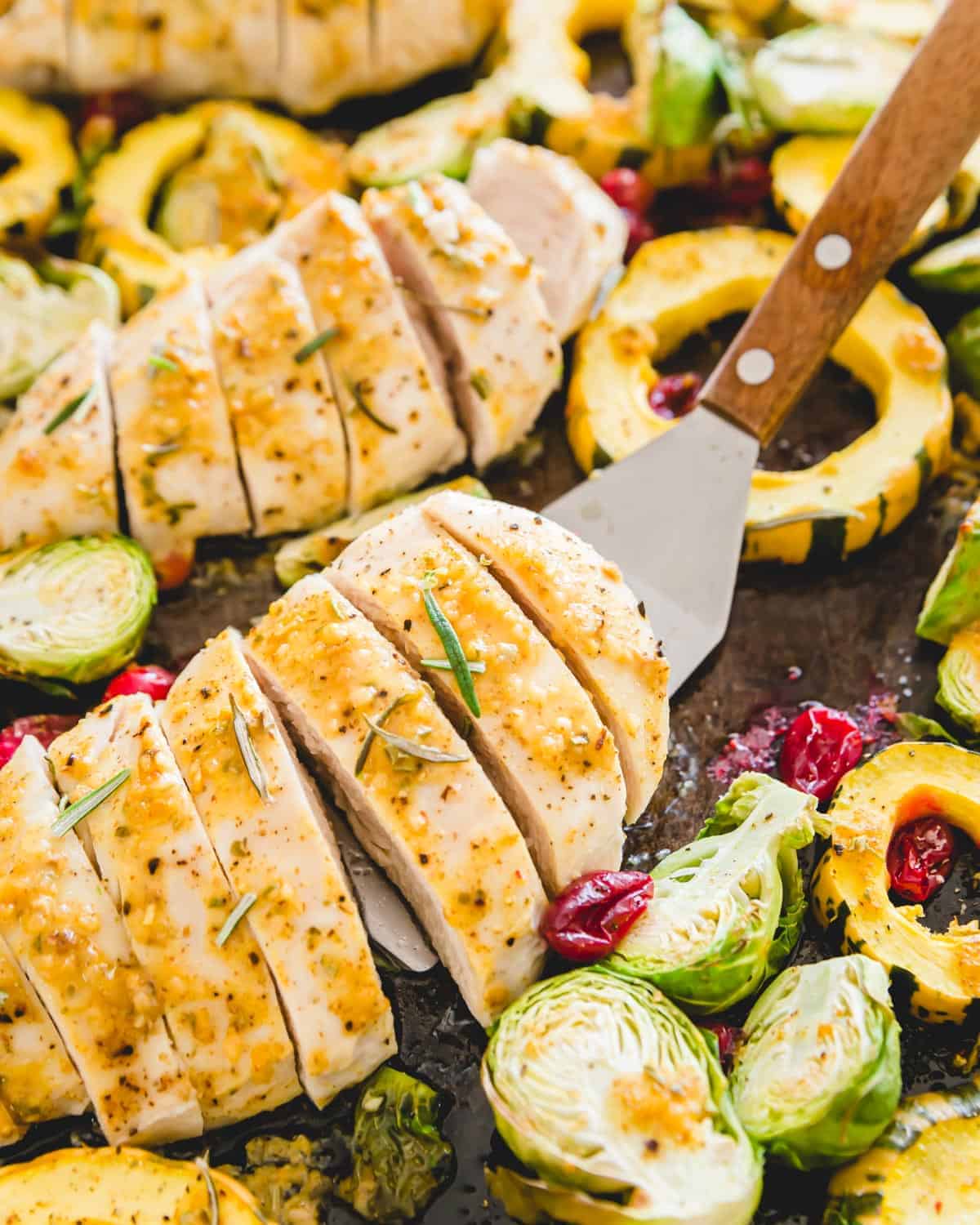 This simple dinner includes maple mustard chicken breasts along with Brussels sprouts, delicata squash and cranberries all baked together on one pan