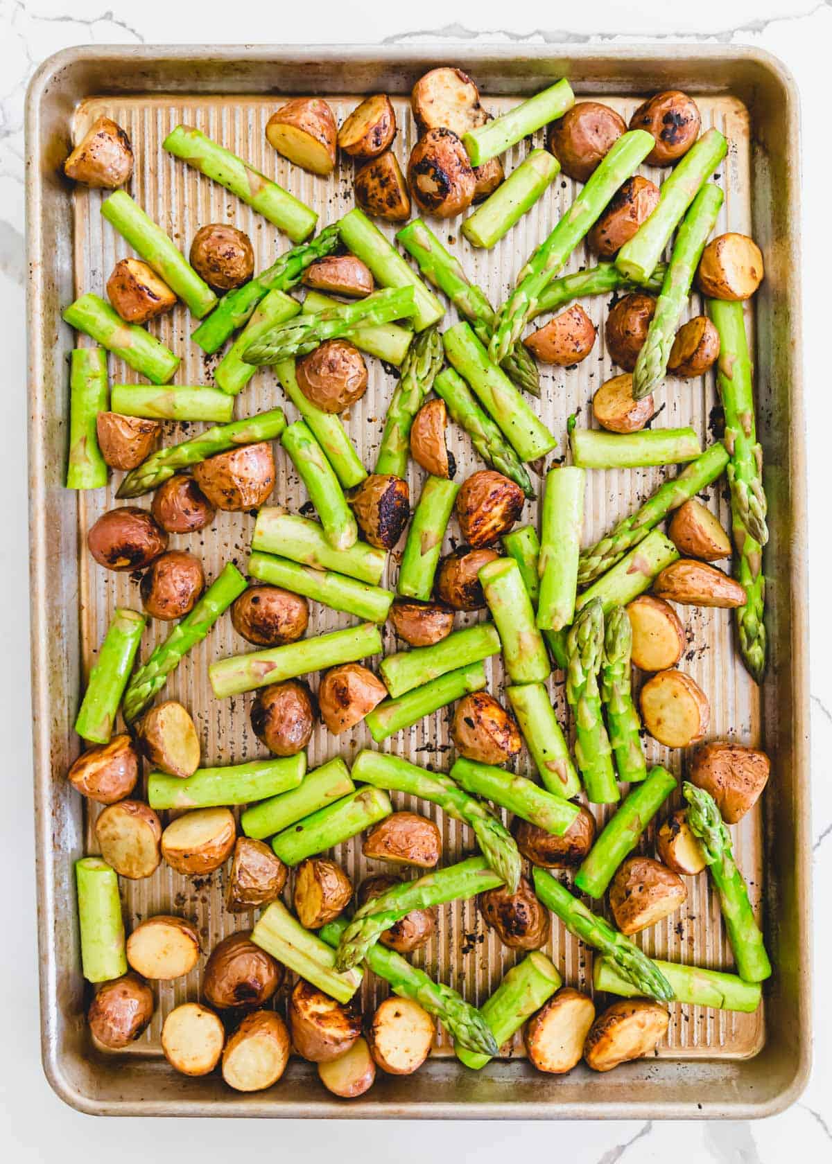 roasted red potatoes with fresh asparagus spears on a baking sheet