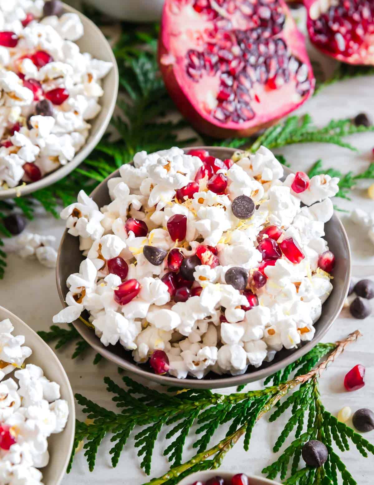 This winter themed popcorn mix includes festive pomegranate arils, dark chocolate chips and lemon zest. A simple and irresistible snack!