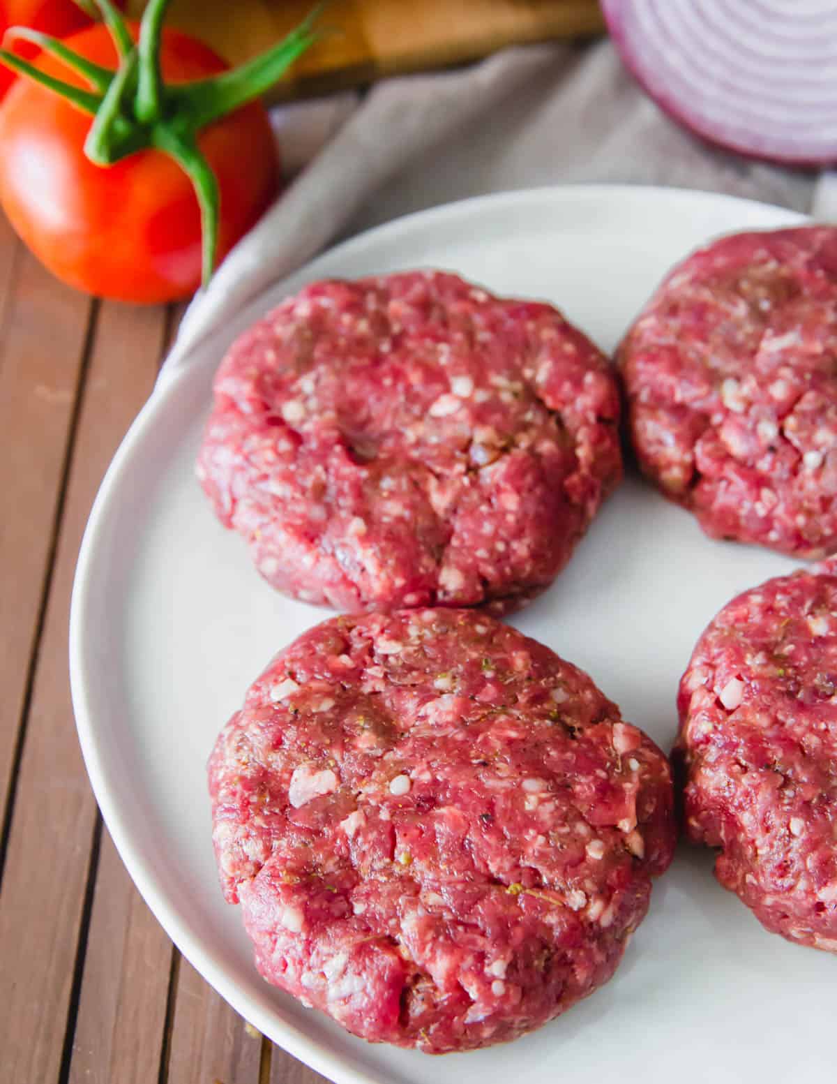 Elk burger patties before grilling on a plate.