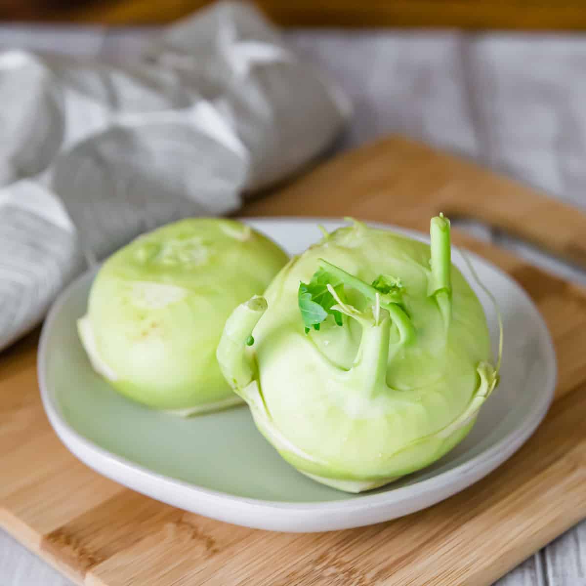 Raw kohlrabi on a plate before being sliced and roasted in the oven.