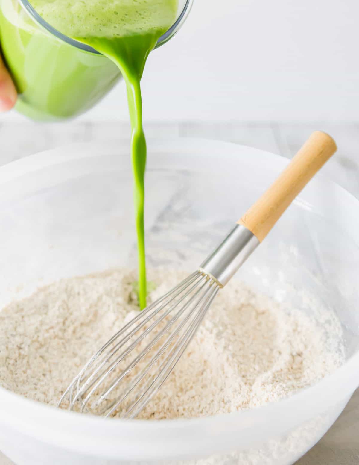 The spinach almond milk blended mixture with maple syrup, vanilla and avocado oil is poured into the dry ingredients to make green pancakes.