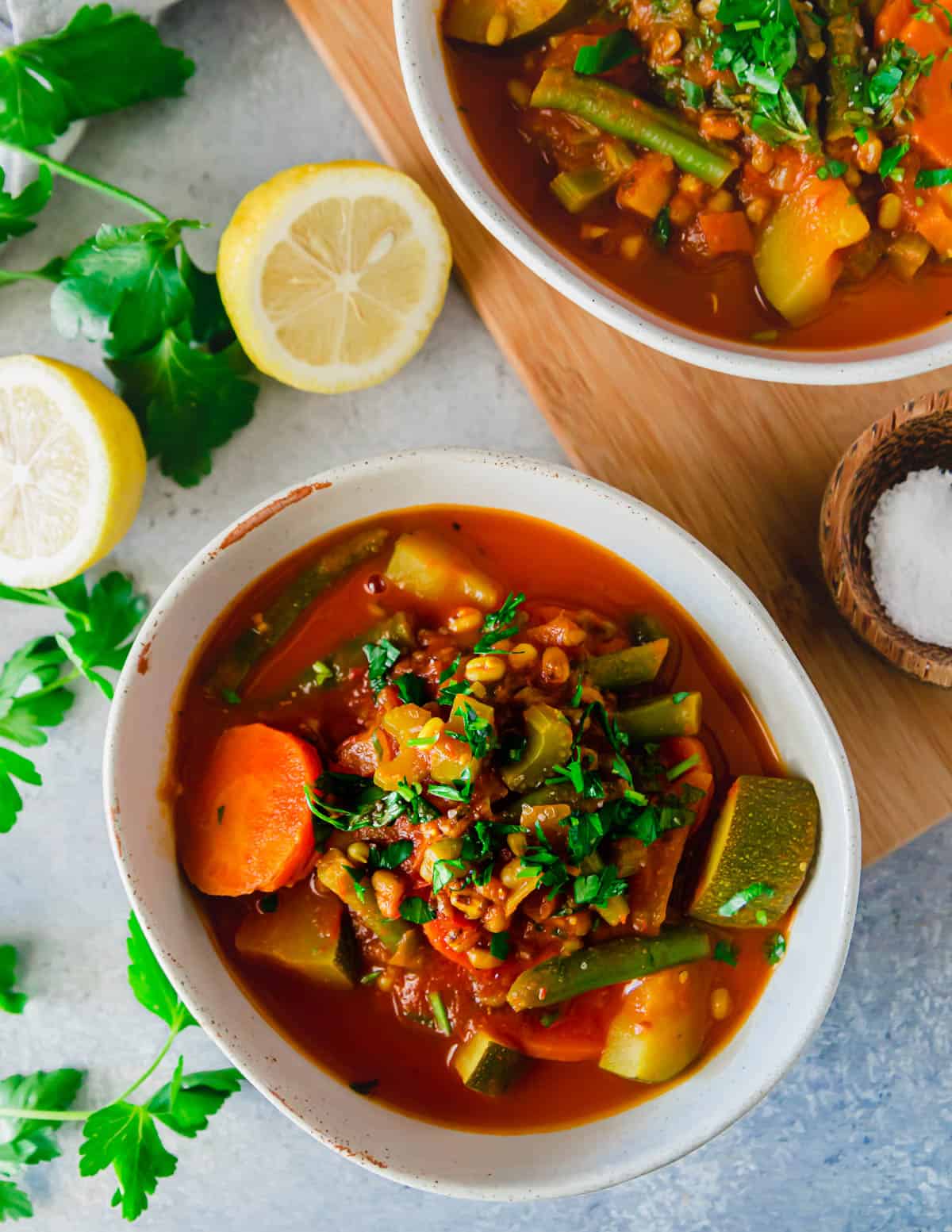 A bowl of vegetable mung bean soup garnished with fresh parsley.