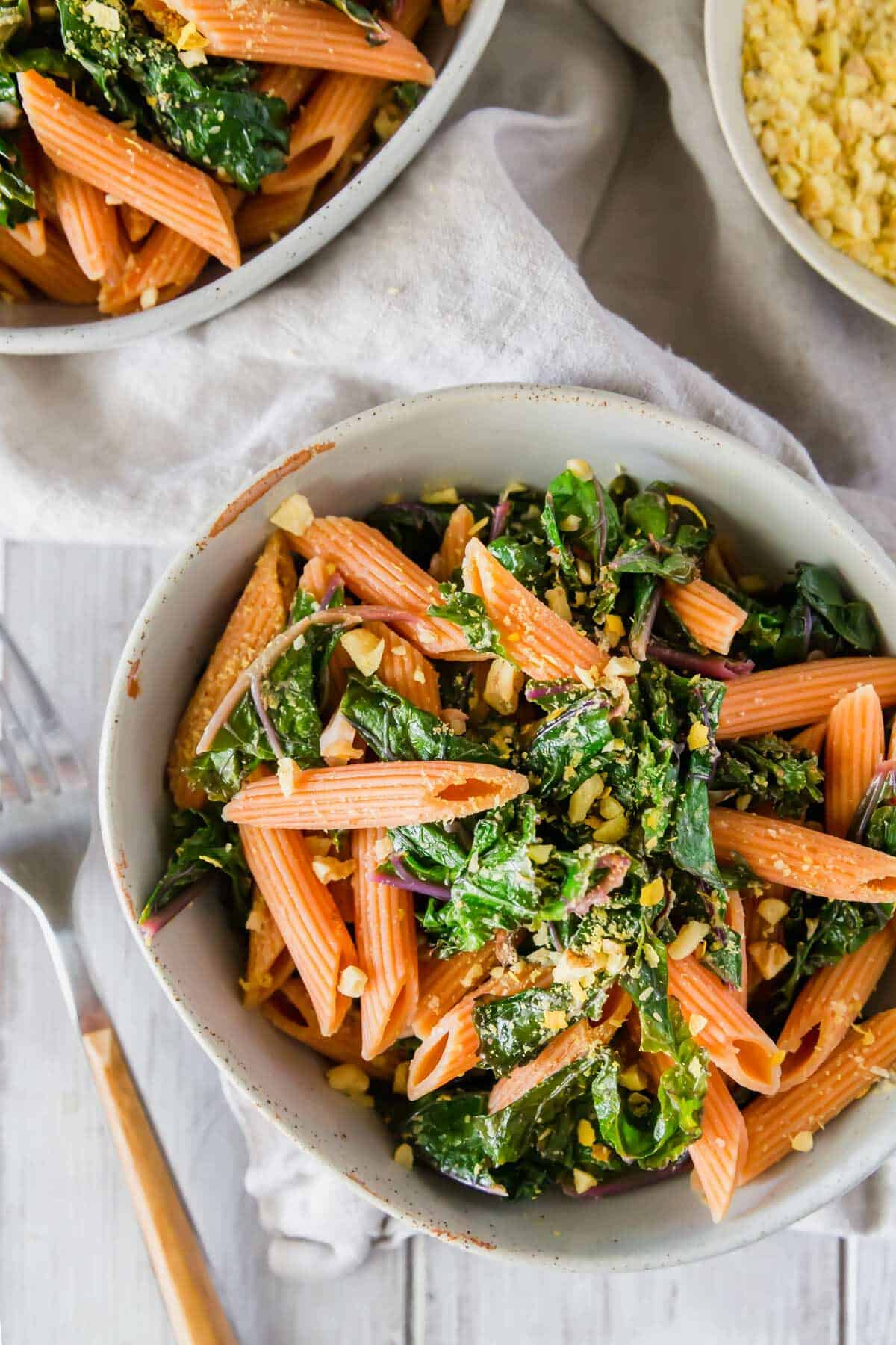 Enjoy this gluten-free red lentil pasta recipe with garlickly lemon kale and a vegan walnut nutritional yeast topping for an easy and nutritious dinner.