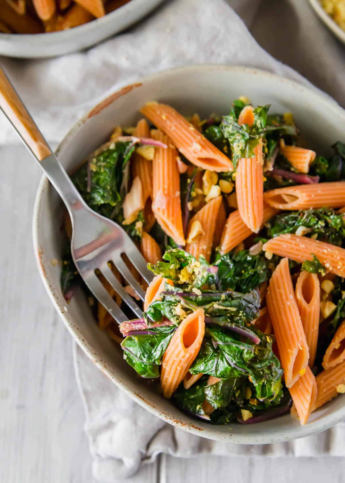 Red lentil pasta with greens in a bowl.