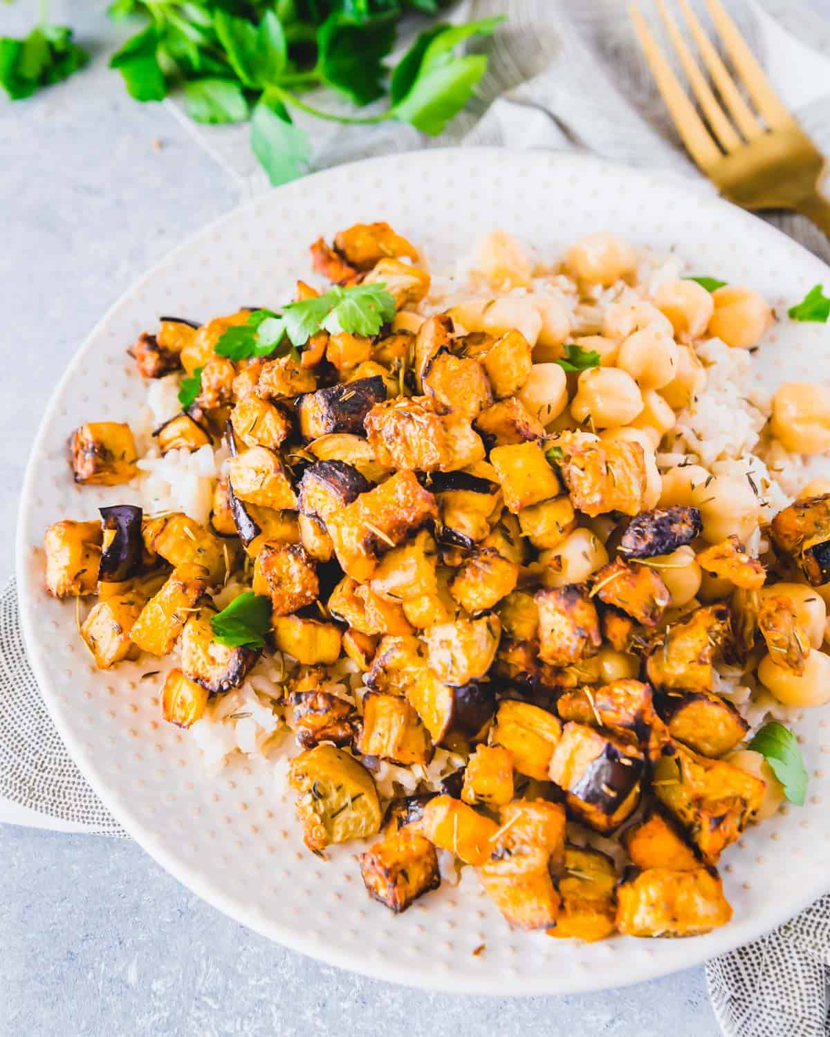 Serving air fryer eggplant on a plate with brown rice and chickpeas for a delicious vegetarian meal.