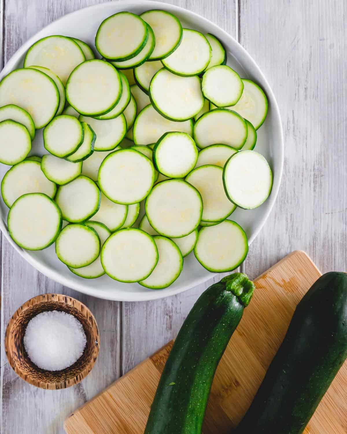 Thinly sliced zucchini on a plate to make zucchini chips in the air fryer.