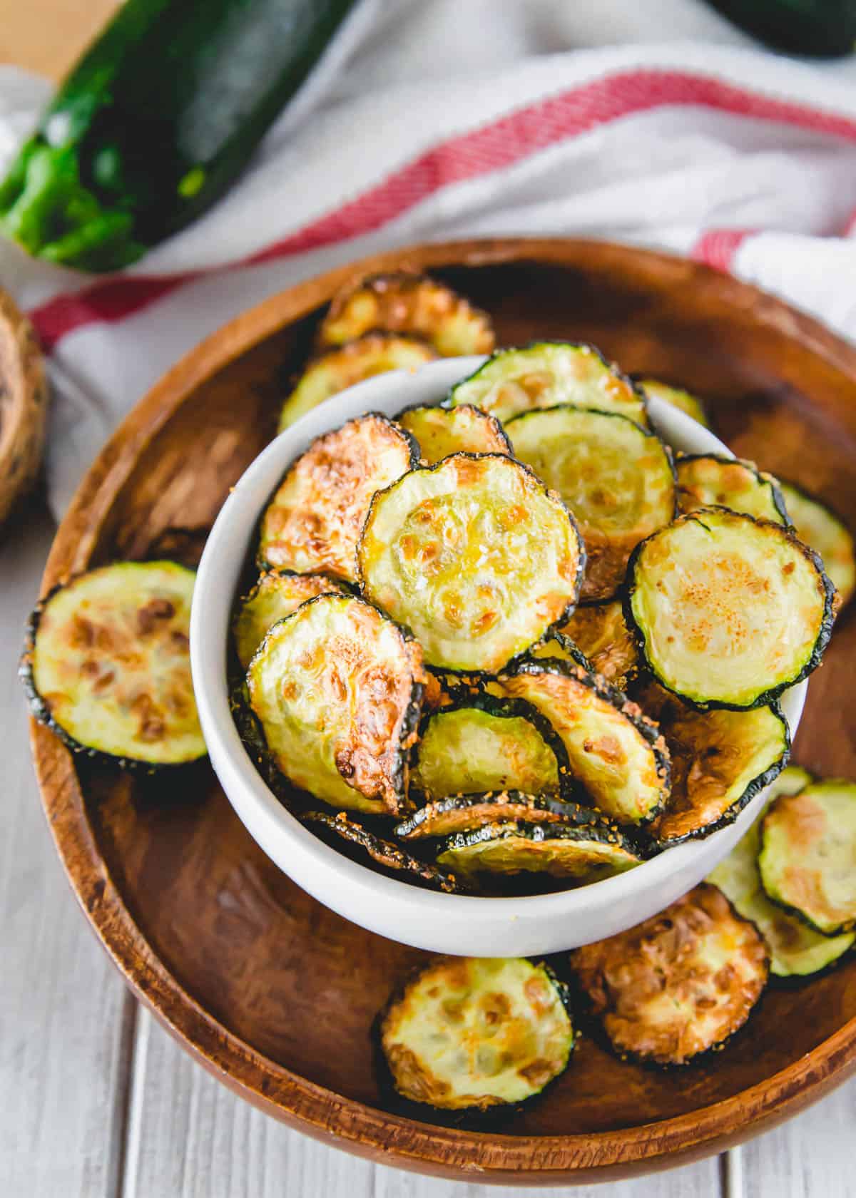 Crispy air fryer zucchini chips in a bowl on a plate.