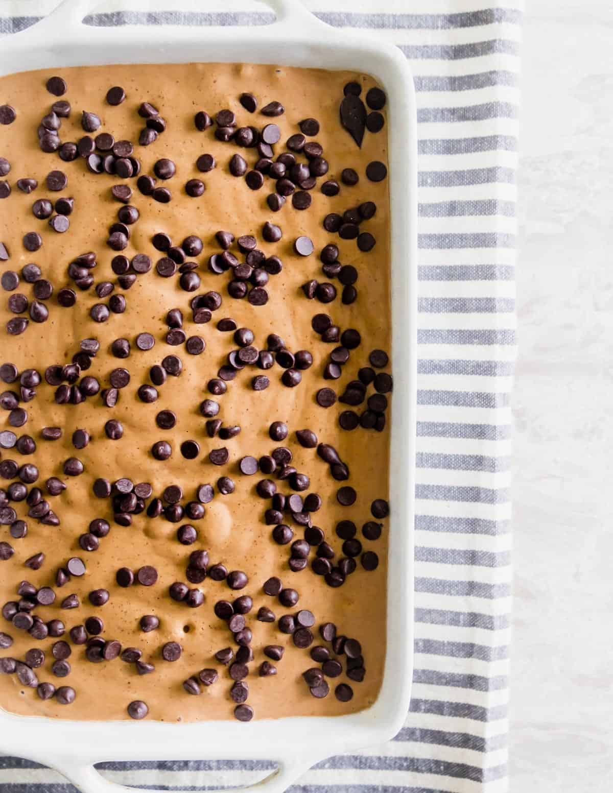 Blended ingredients for baked oats are poured into a baking dish and topped with chocolate chips before being baked in the oven.