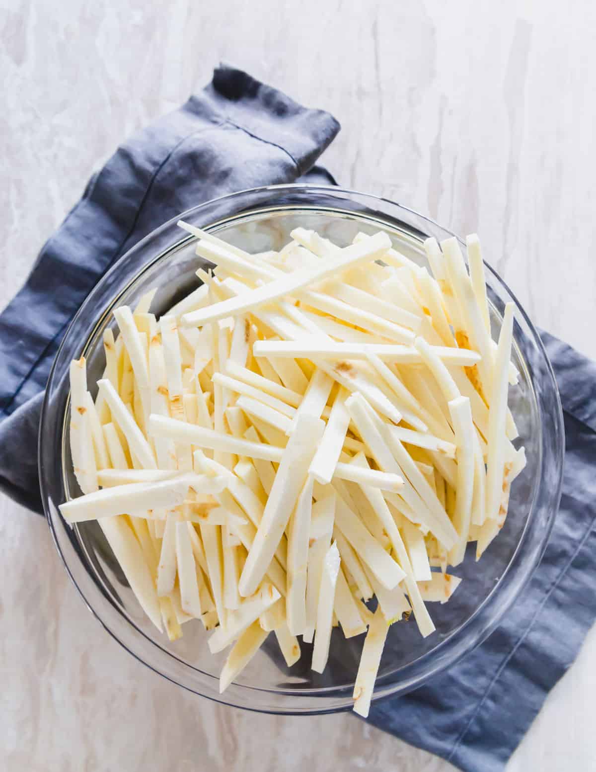 Raw parsnips cut into "fries" or matchsticks in a bowl.
