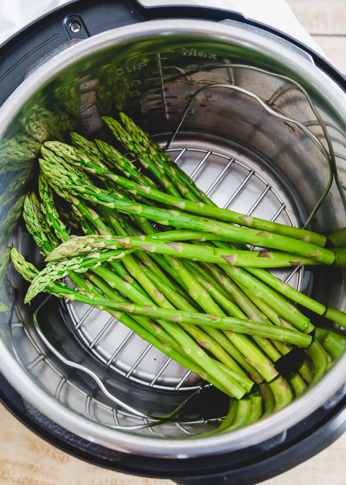 Raw asparagus spears inside an Instant Pot atop the metal trivet.