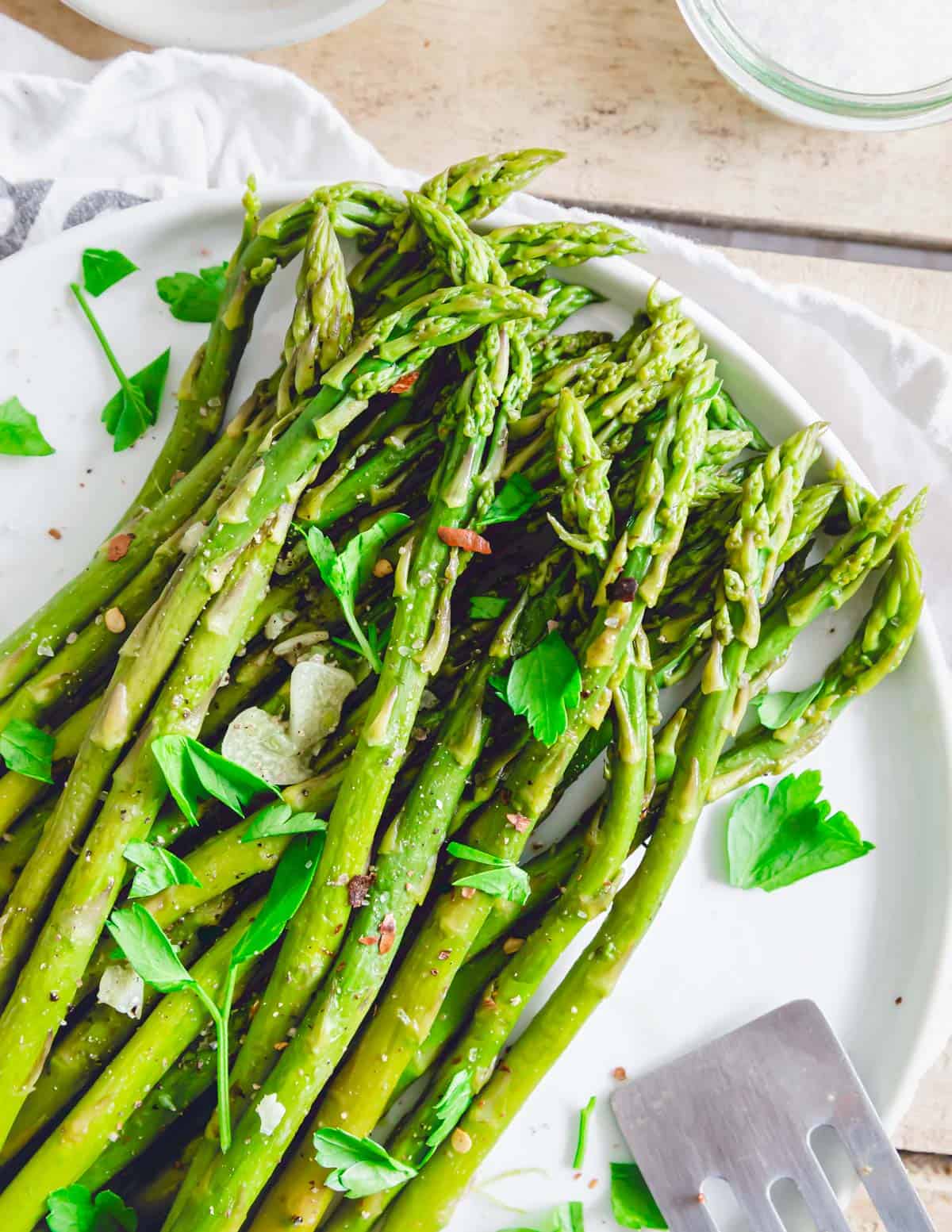 Tender asparagus made in the Instant Pot on a plate with olive oil, butter, garlic and chili flakes.