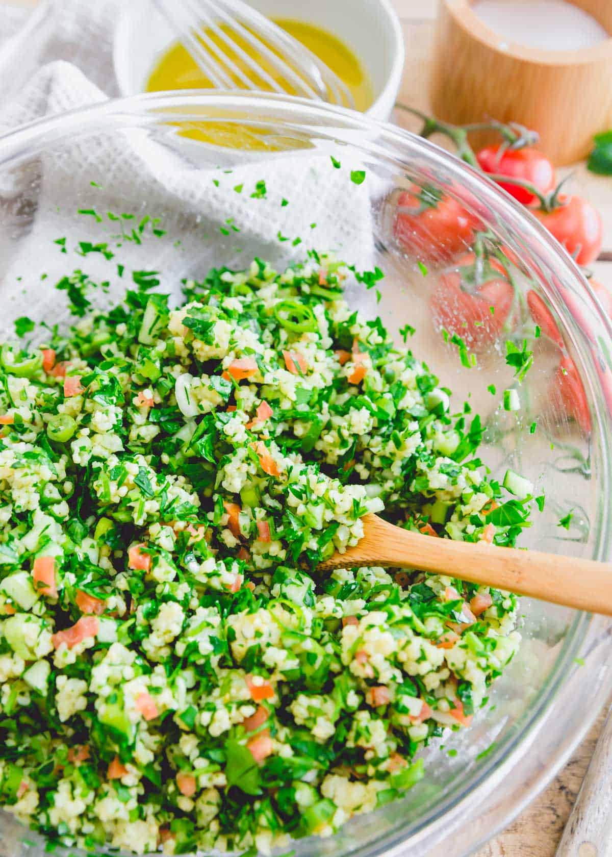 Prepping gluten-free millet tabbouleh in a glass bowl.