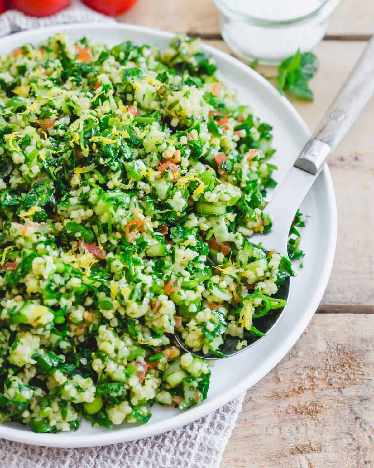 Millet tabbouleh recipe on a serving plate with a serving spoon.