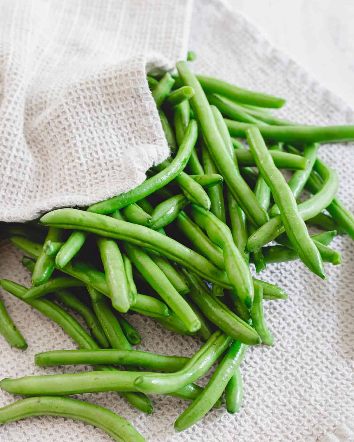 Freshly washed and trimmed green beans on a kitchen towel.