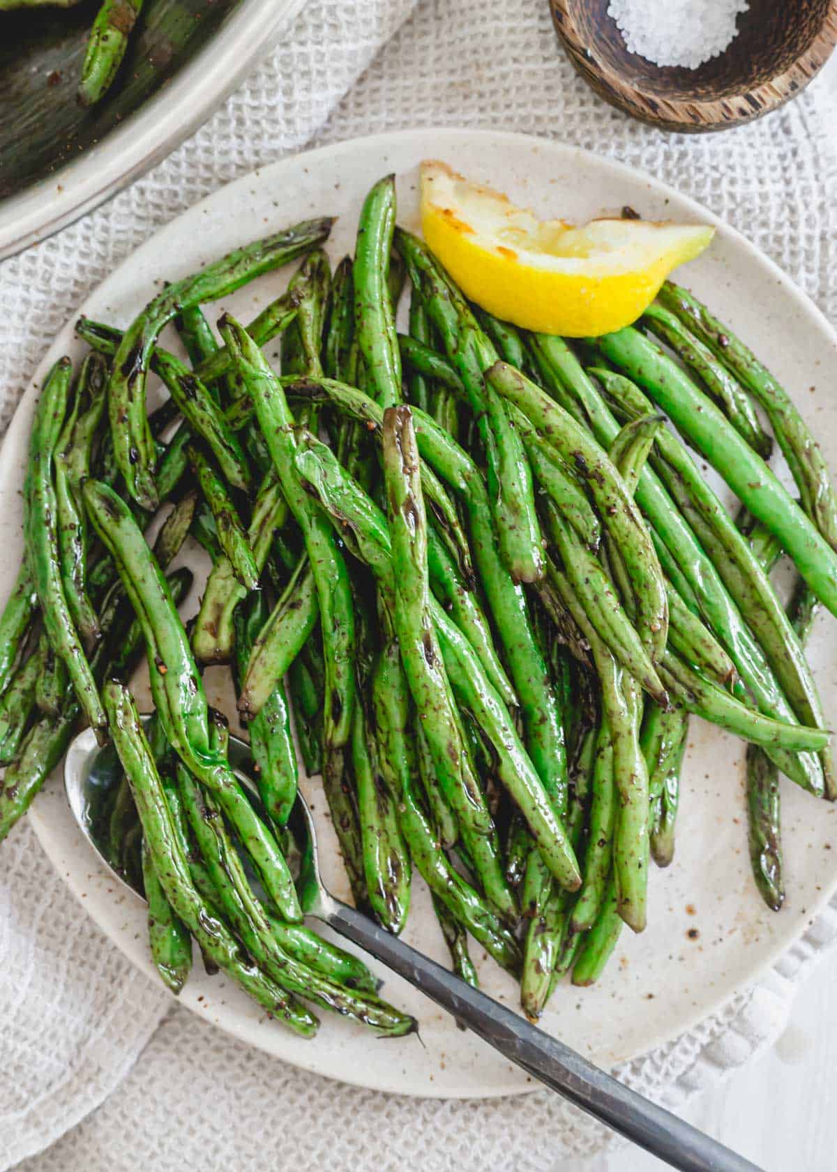 Grilled green beans with lemon on a plate.