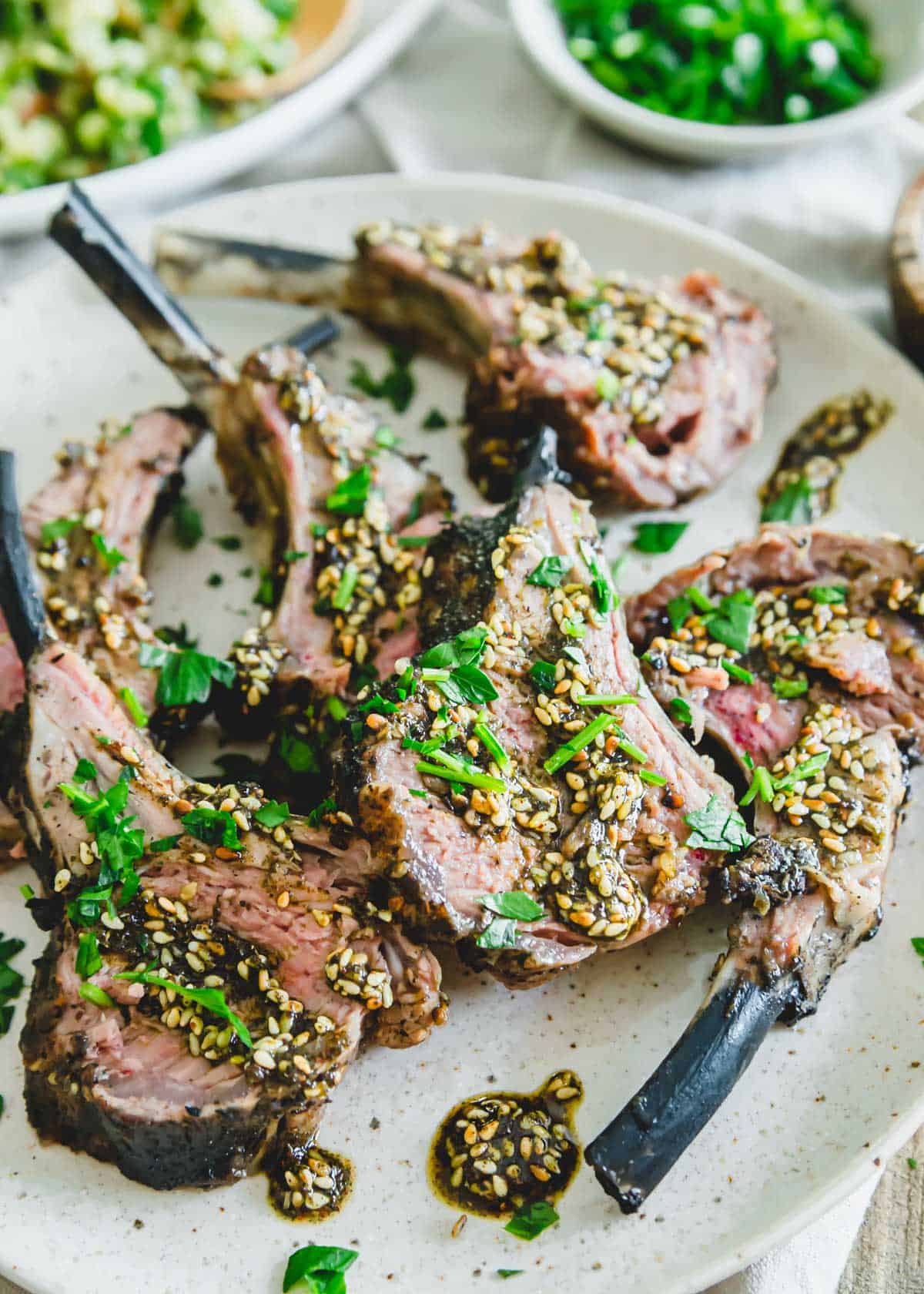 Za'atar grilled rack of lamb garnished with fresh parsley on a plate.
