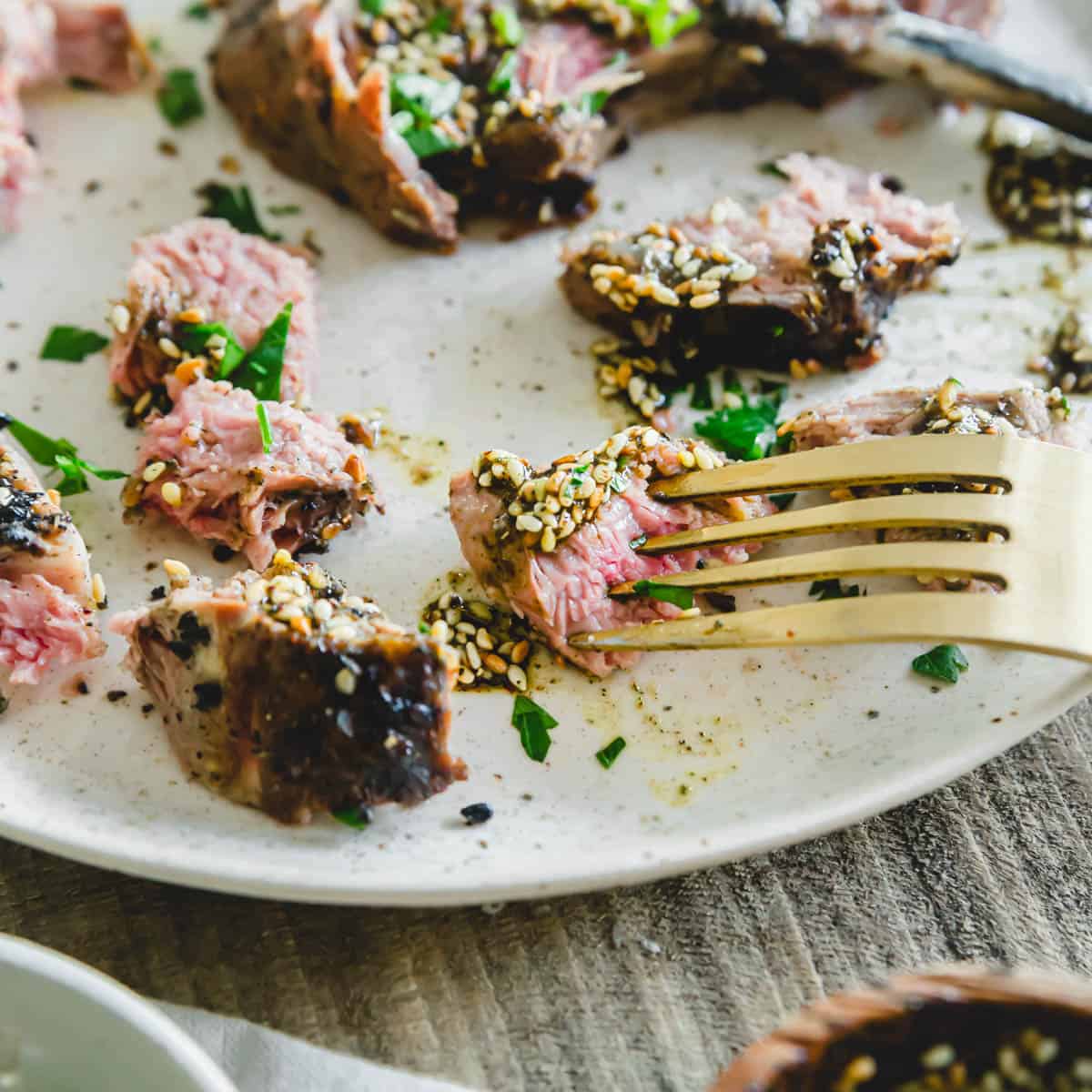 Cut up za'atar spiced grilled lamb chop on a plate with a fork.