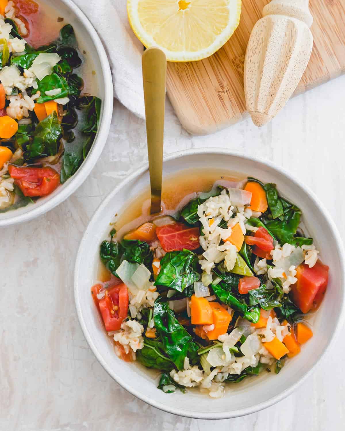 Simple Tuscan kale soup with carrots, onions, celery, diced tomatoes and brown rice in a bowl with a spoon.