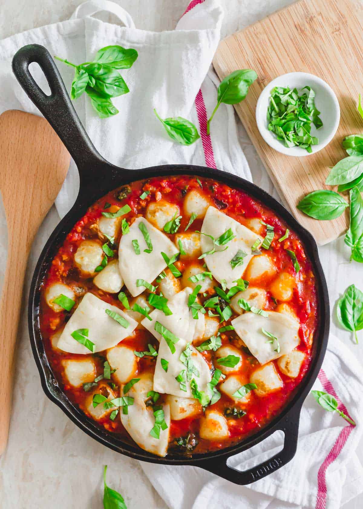 Finished baked cauliflower gnocchi recipe in a skillet garnished with fresh basil.