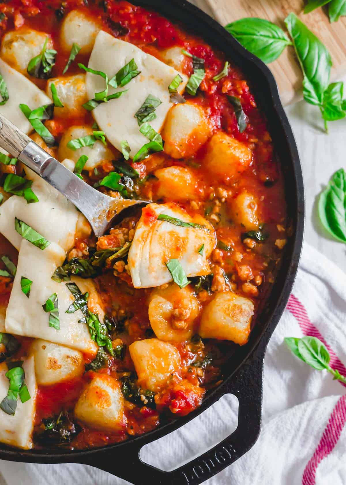 Skillet baked cauliflower gnocchi recipe with pork, tomatoes, spinach and mozzarella.