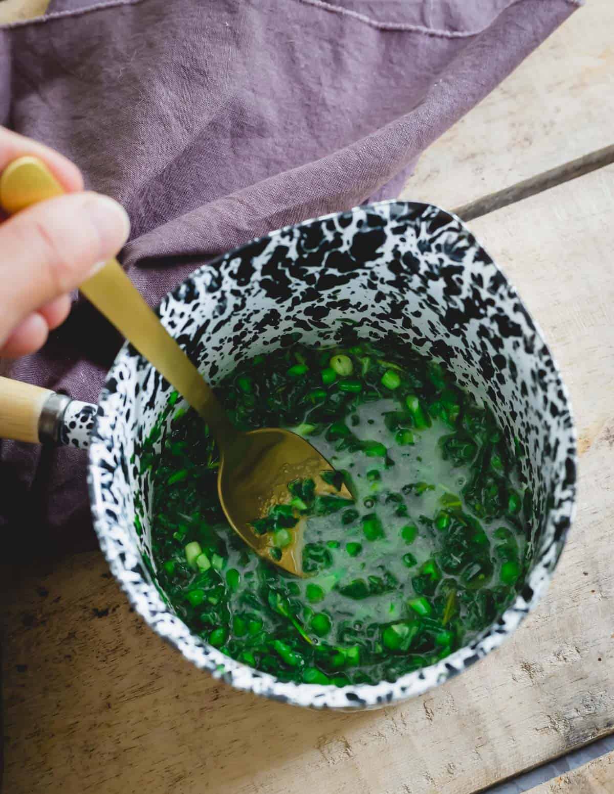 Making an herb butter sauce with ghee, fresh sage, thyme and garlic in a small pot.