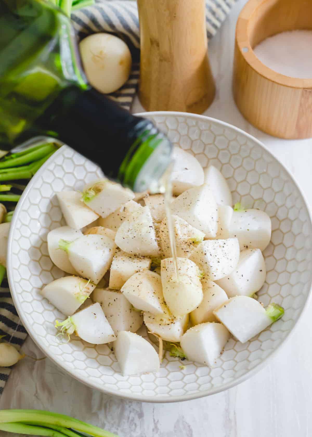 Chopped Japanese turnips with olive oil, salt and pepper in a bowl.