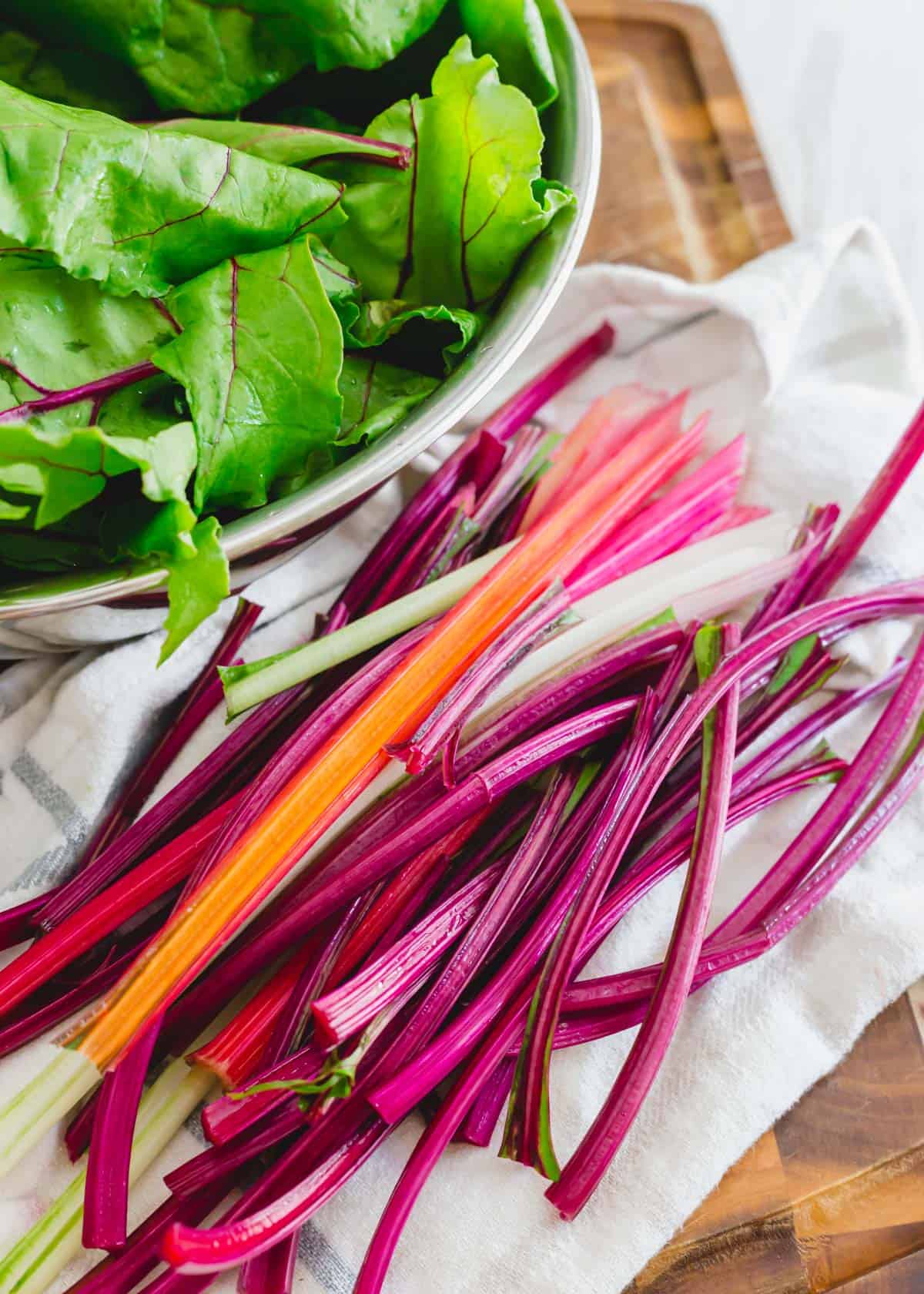 Rainbow Swiss chard stems and beet greens stems with a bowl of greens in the background.