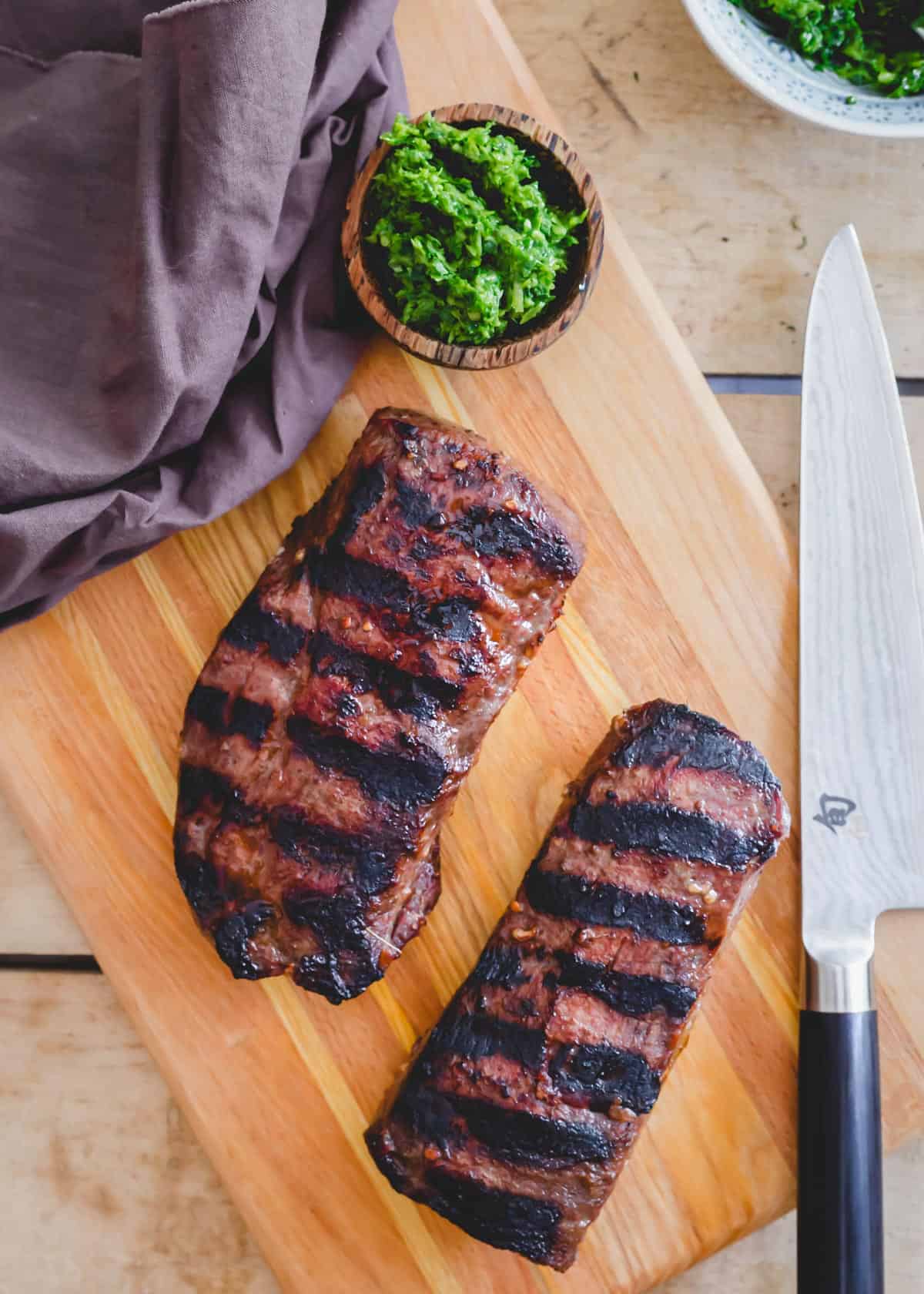 Two pieces of grilled venison backstrap on a cutting board.