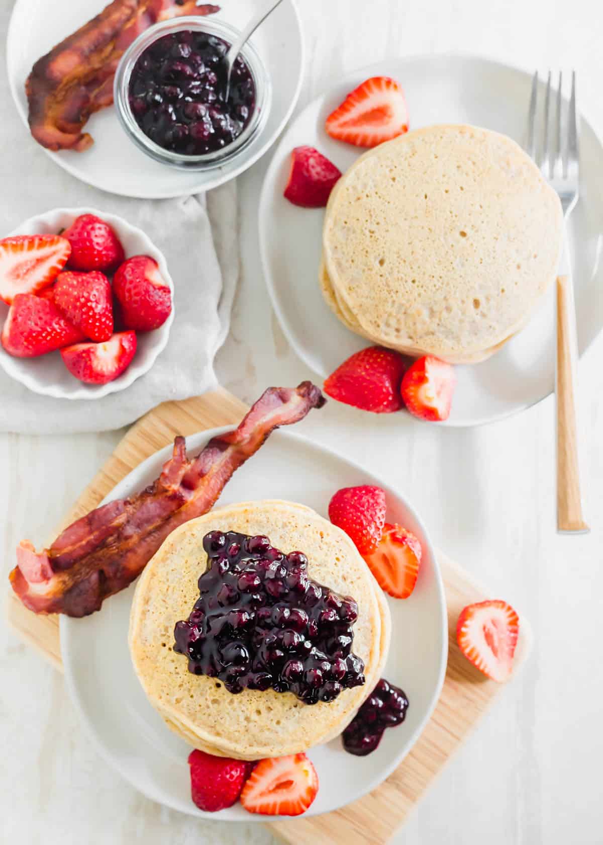Stacks of cassava flour pancakes with strawberries and bacon.