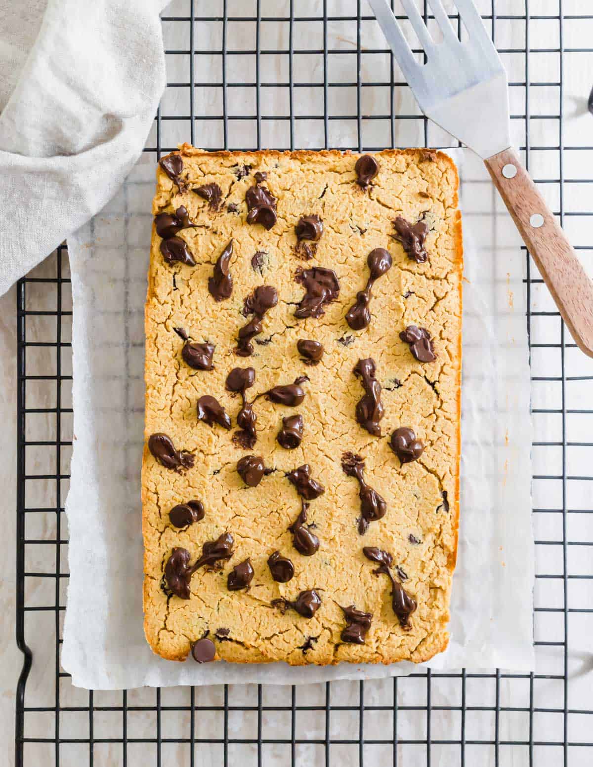 Baked chocolate chip chickpea blondies on a cooling rack.