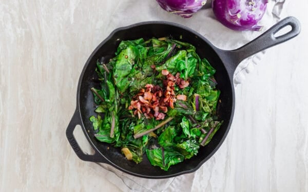 Bacon topped cooked kohlrabi greens with garlic and scallions.
