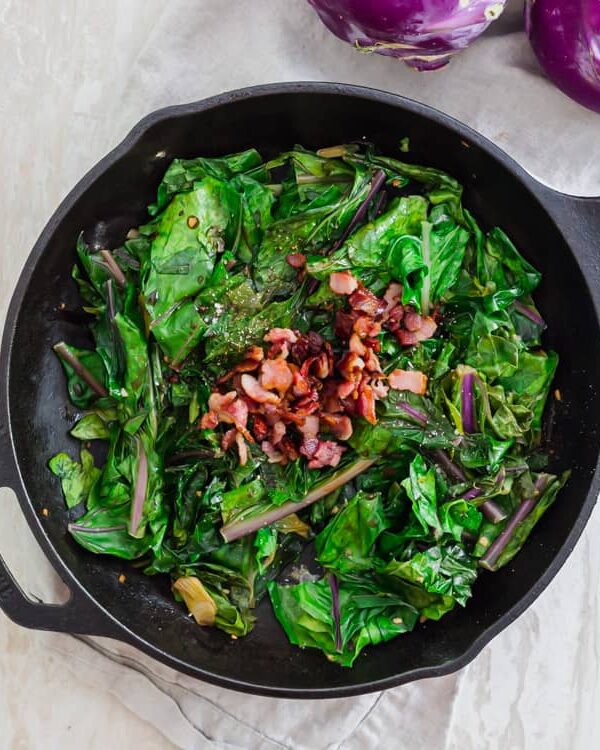 Bacon topped cooked kohlrabi greens with garlic and scallions.