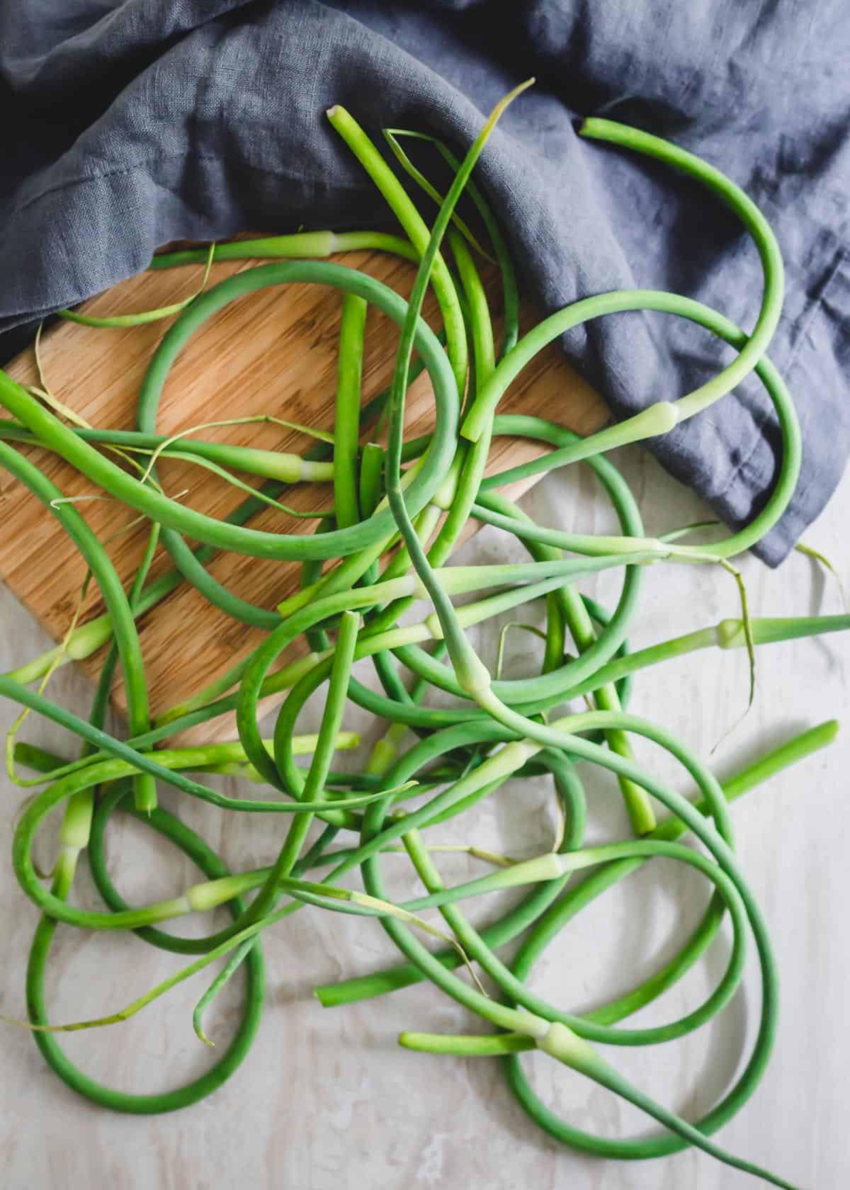 Fresh garlic scapes on a cutting board.