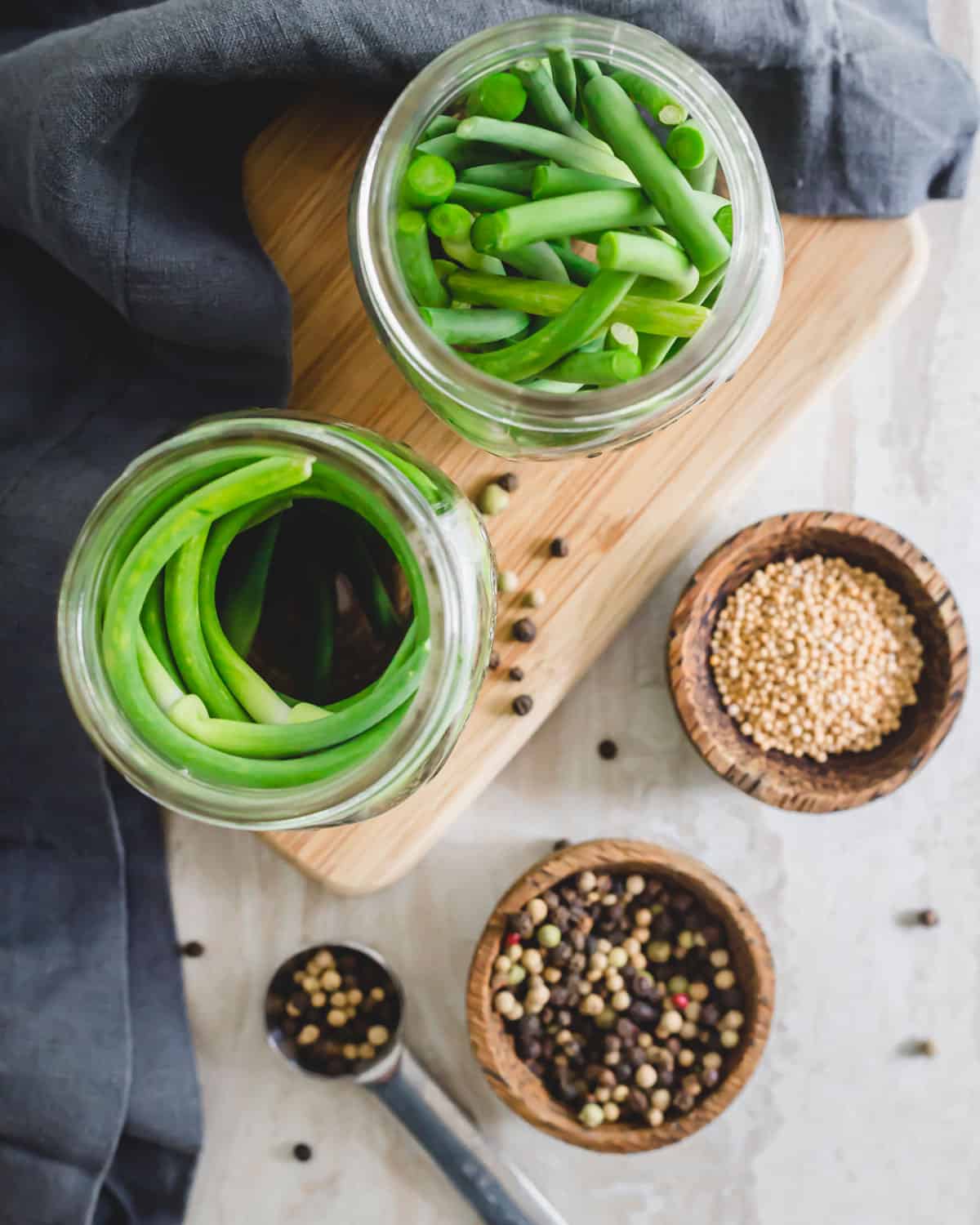 Cut garlic scapes fit into mason jars before pouring pickling liquid.