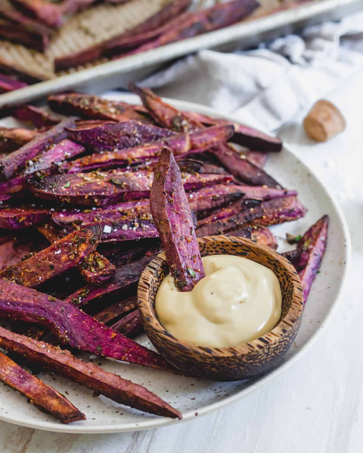 Oven baked purple sweet potato fries on a plate with mayo based dip.