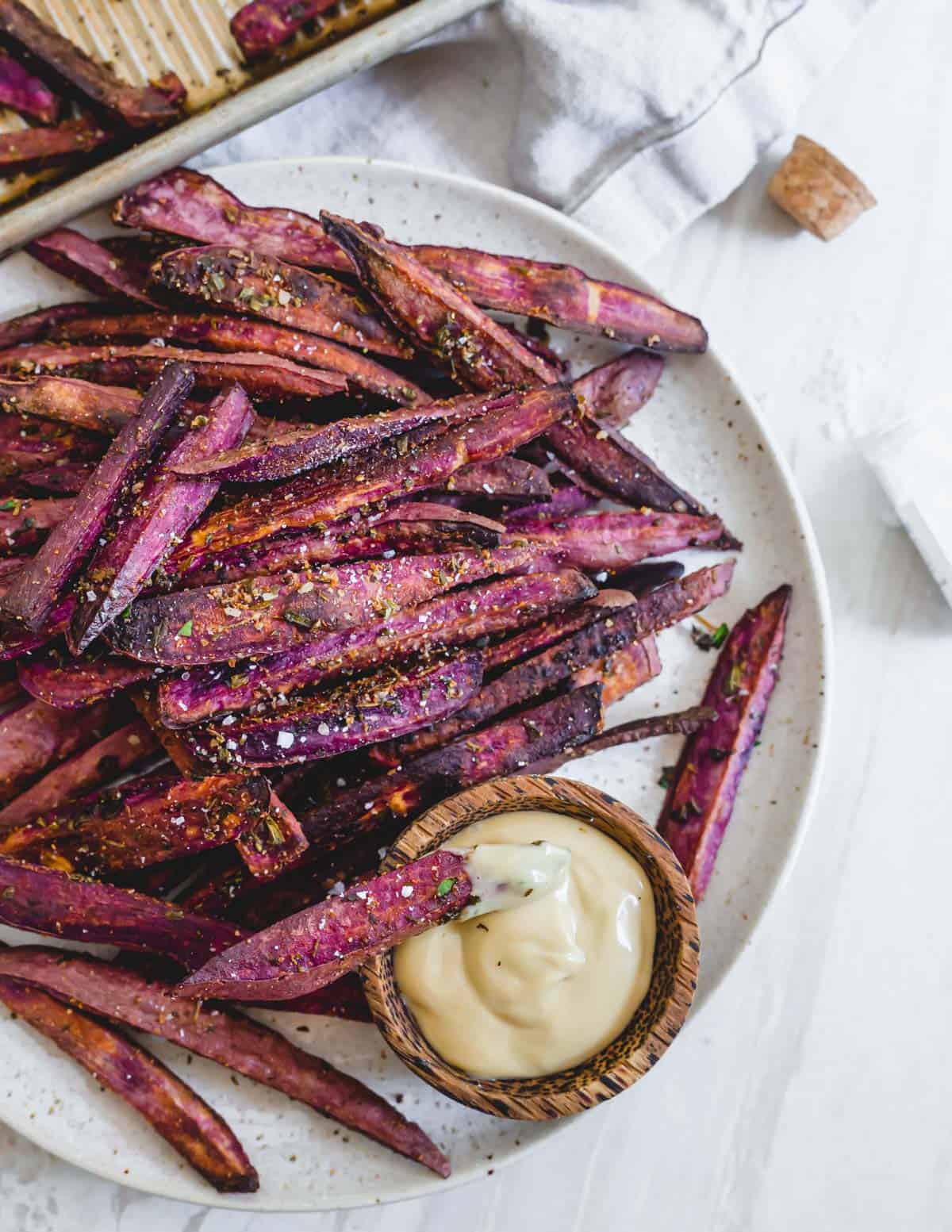 Healthy purple sweet potato fries with fresh herbs, oil and sea salt with mayo dipping sauce.