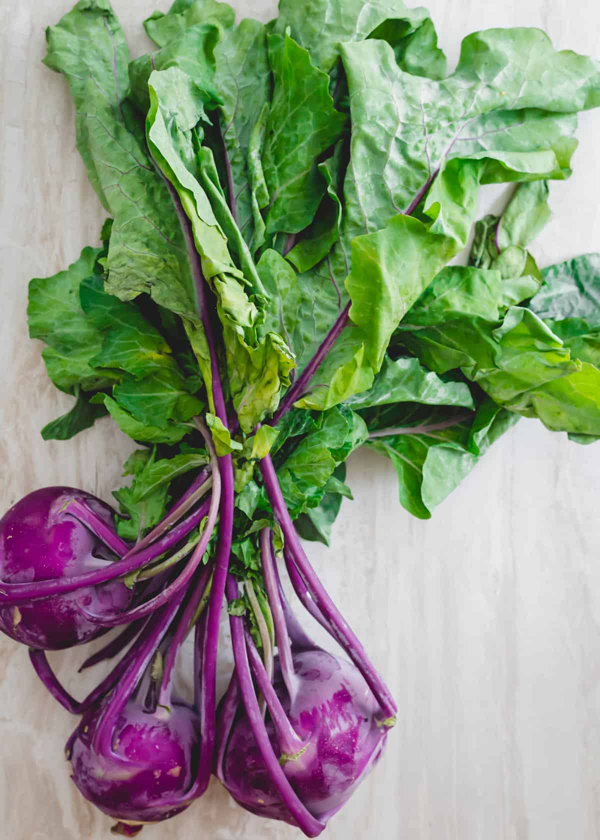 Purple kohlrabi with greens attached.