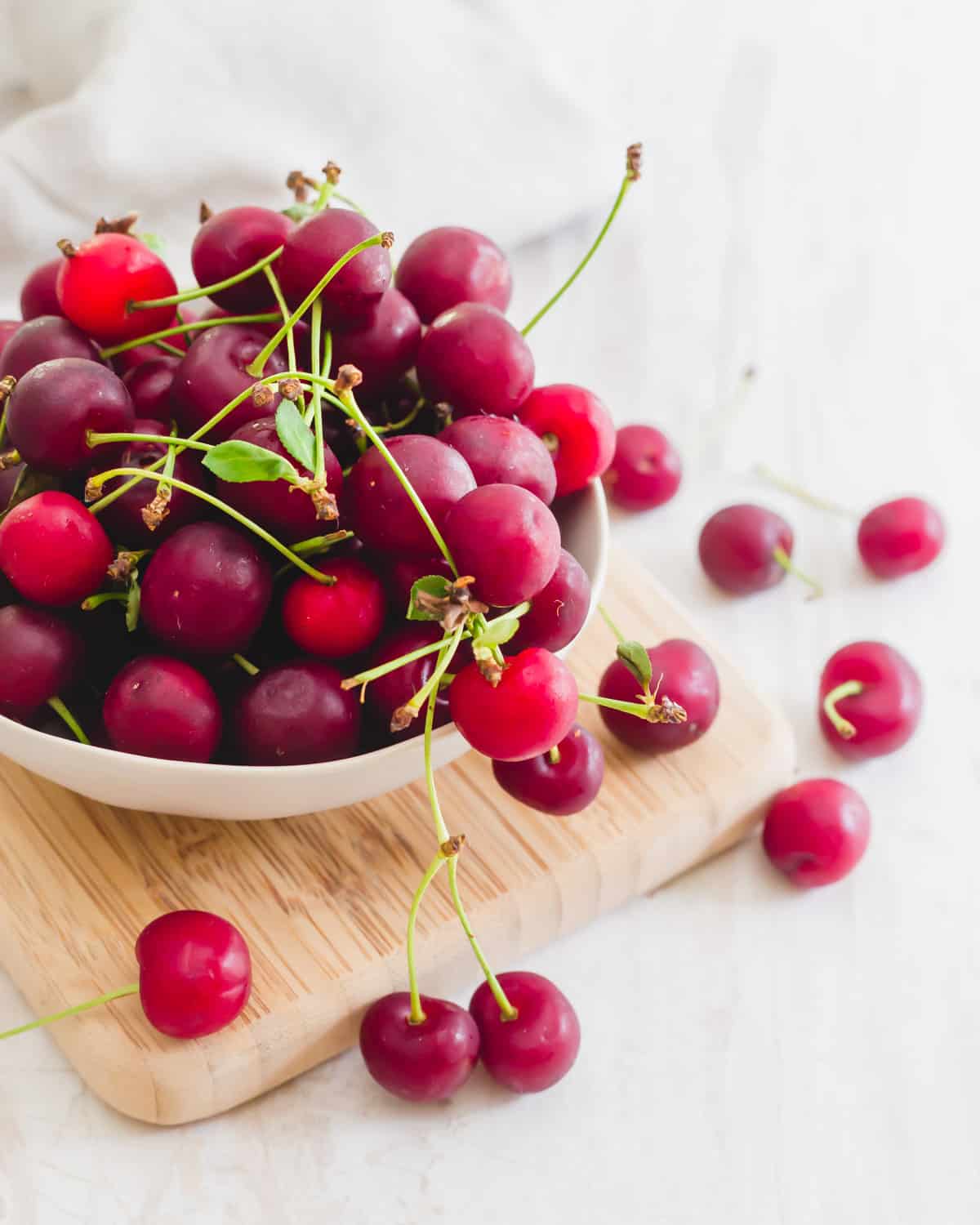 Fresh sour (tart) cherries in a bowl on a cutting board.