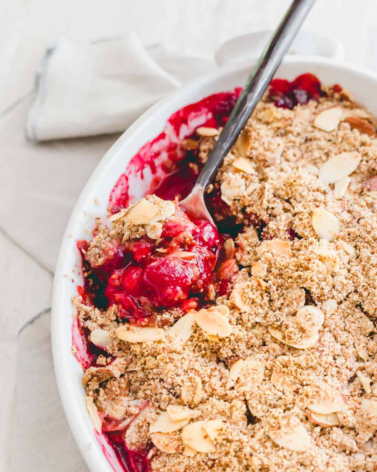 Baked sour cherry crisp with a serving spoon.